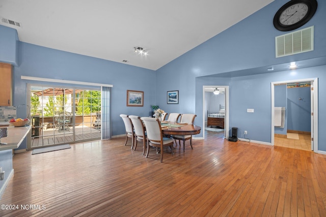 dining room featuring light wood finished floors, visible vents, and high vaulted ceiling