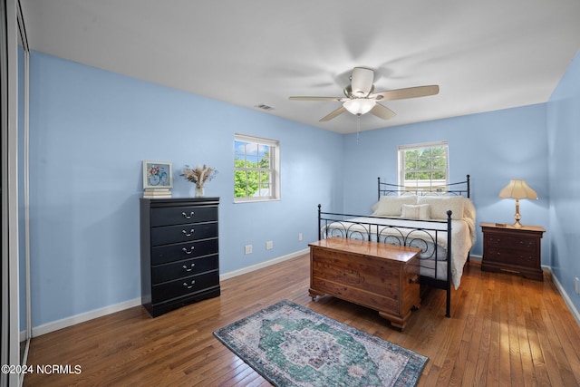 bedroom featuring wood-type flooring, multiple windows, visible vents, and baseboards