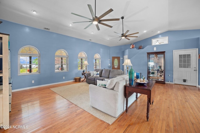 living room featuring a wealth of natural light, light wood-type flooring, visible vents, and vaulted ceiling