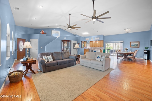 living area featuring high vaulted ceiling, light wood-type flooring, visible vents, and a ceiling fan