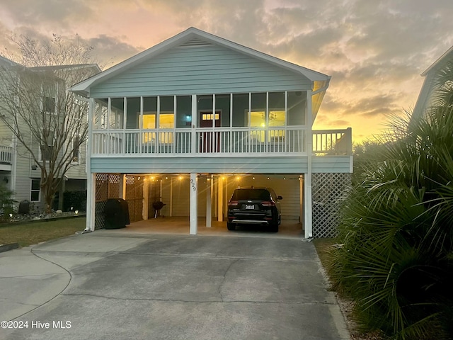 raised beach house featuring a sunroom and a carport