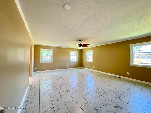 unfurnished room featuring ceiling fan, ornamental molding, a textured ceiling, and a wealth of natural light