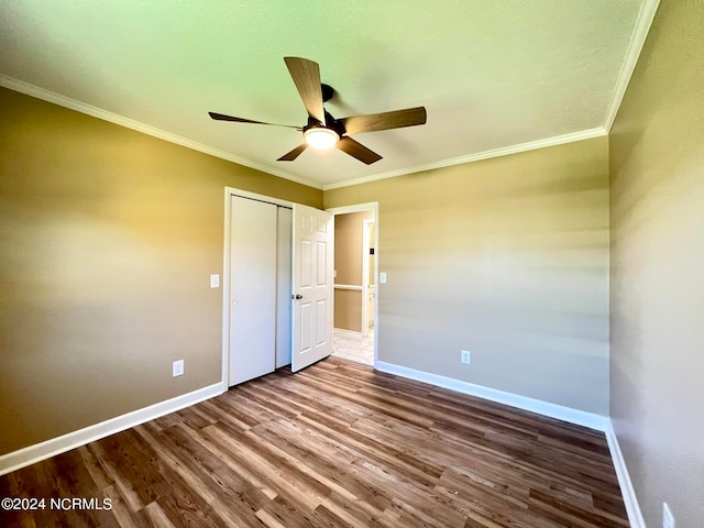 unfurnished bedroom with ceiling fan, a closet, wood-type flooring, and ornamental molding