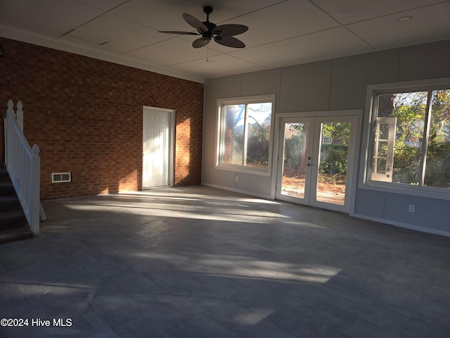 interior space featuring ceiling fan, french doors, and brick wall