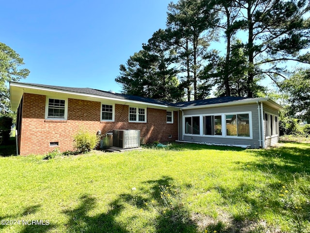 rear view of house featuring a lawn and central AC