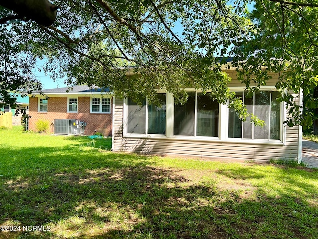 rear view of house featuring a lawn and central AC unit