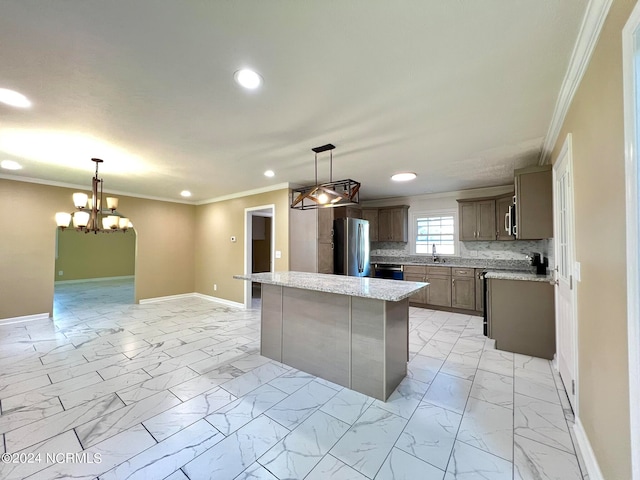 kitchen with hanging light fixtures, decorative backsplash, ornamental molding, appliances with stainless steel finishes, and a kitchen island