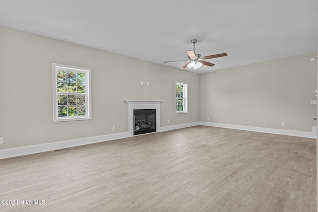 unfurnished living room featuring light wood-type flooring, a healthy amount of sunlight, and ceiling fan