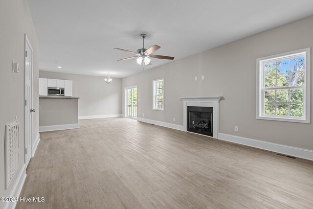 unfurnished living room with light hardwood / wood-style floors and ceiling fan with notable chandelier