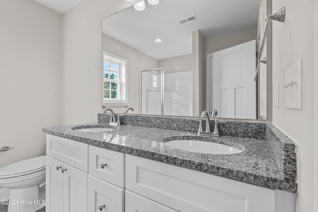 bathroom with a shower with shower door, vanity, and toilet