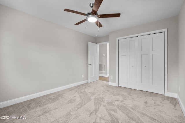 unfurnished bedroom featuring a closet, light colored carpet, and ceiling fan