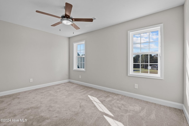 unfurnished room with plenty of natural light, light carpet, and ceiling fan