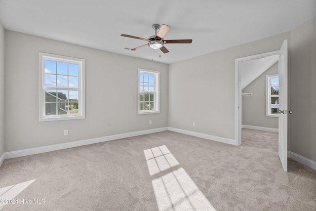 carpeted empty room with a wealth of natural light and ceiling fan