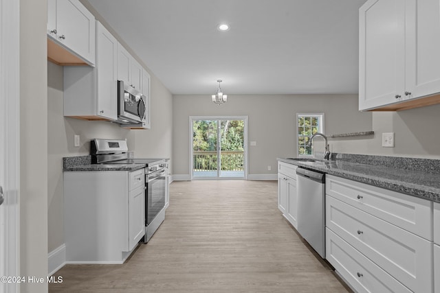 kitchen with light wood-type flooring, appliances with stainless steel finishes, sink, and white cabinets