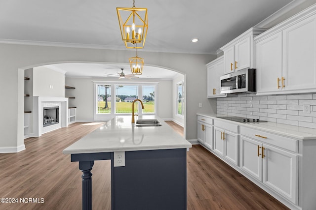 kitchen featuring a kitchen island with sink, ceiling fan with notable chandelier, dark hardwood / wood-style flooring, sink, and decorative backsplash