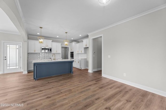 kitchen featuring hardwood / wood-style floors, white cabinetry, a kitchen island with sink, sink, and tasteful backsplash