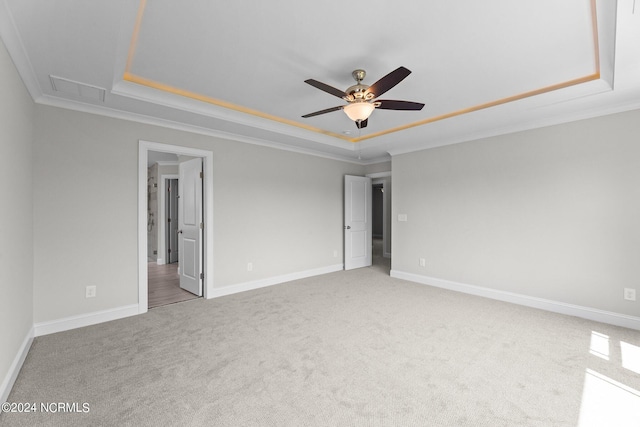 unfurnished bedroom with light colored carpet, a raised ceiling, and ornamental molding