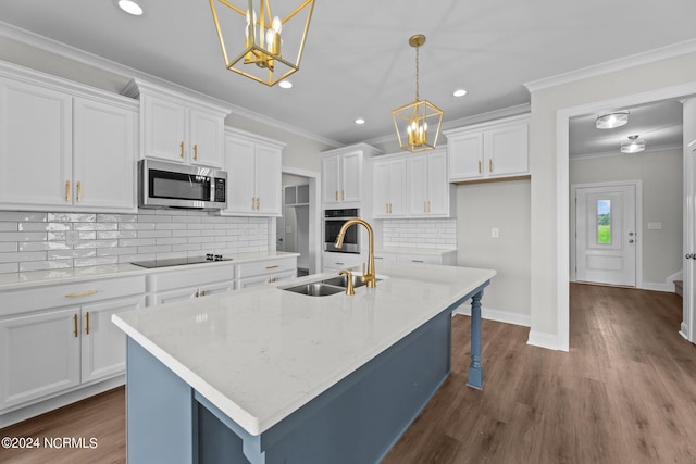 kitchen featuring appliances with stainless steel finishes, white cabinetry, an island with sink, and a chandelier