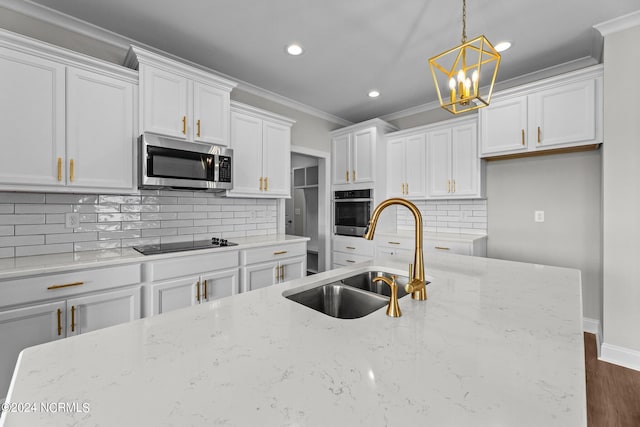 kitchen featuring light stone countertops, a notable chandelier, stainless steel appliances, sink, and decorative backsplash