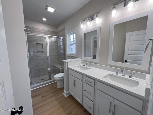 bathroom with hardwood / wood-style flooring, toilet, vanity, and walk in shower