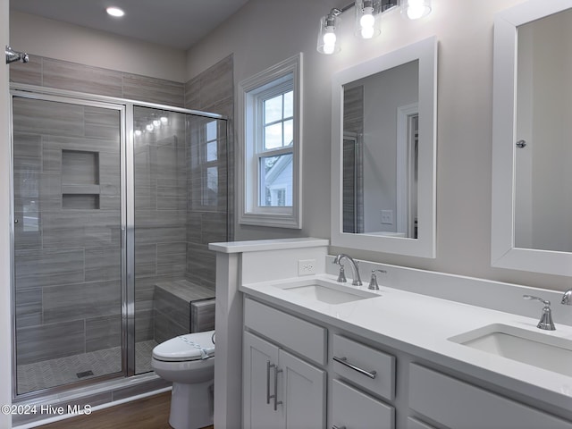 bathroom with hardwood / wood-style floors, toilet, vanity, and an enclosed shower