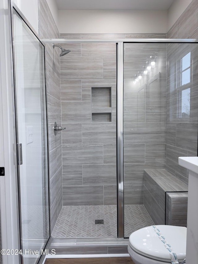 bathroom with a shower with shower door and toilet