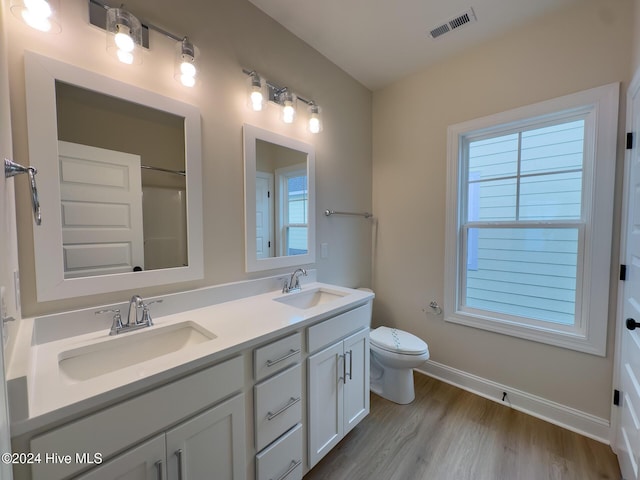 bathroom with hardwood / wood-style floors, toilet, vanity, and a wealth of natural light