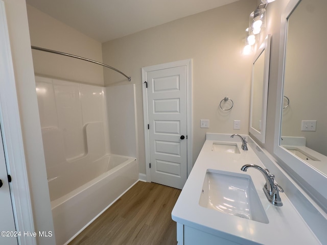 bathroom with hardwood / wood-style floors, washtub / shower combination, and vanity