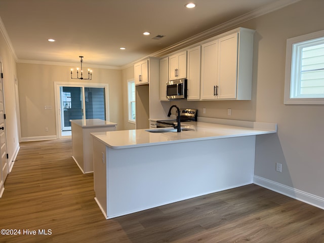 kitchen with white cabinetry, kitchen peninsula, dark wood-type flooring, hanging light fixtures, and sink