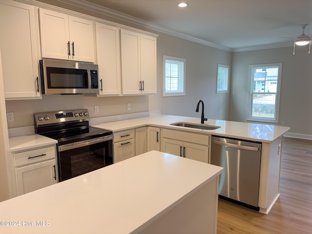 kitchen with kitchen peninsula, sink, white cabinetry, a healthy amount of sunlight, and appliances with stainless steel finishes