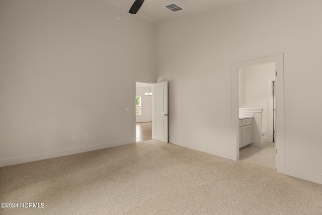 carpeted spare room with ceiling fan and a high ceiling