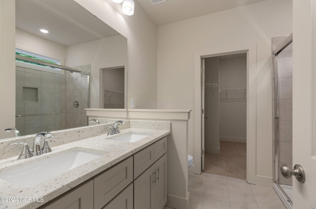 bathroom featuring walk in shower, toilet, tile patterned floors, and double sink vanity