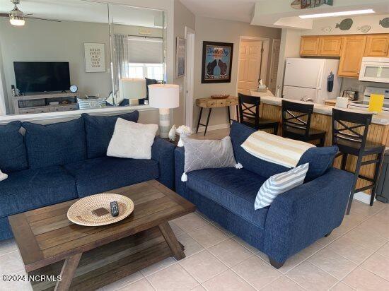 living area with light tile patterned floors and a ceiling fan