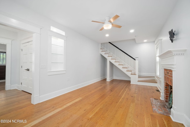 unfurnished living room with a fireplace, ceiling fan, and light hardwood / wood-style flooring