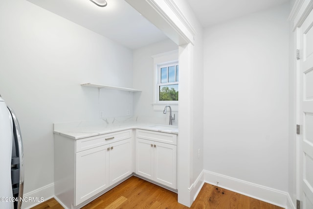 interior space featuring light hardwood / wood-style floors, cabinets, sink, and washer / clothes dryer