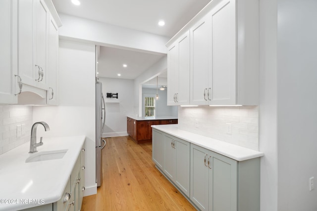 kitchen featuring tasteful backsplash, white cabinetry, sink, and light hardwood / wood-style flooring