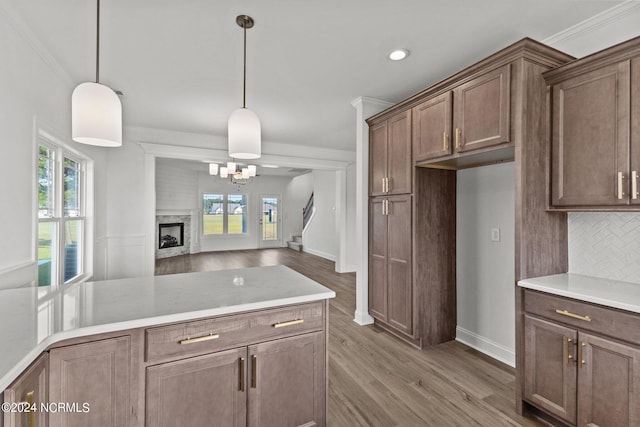 kitchen with backsplash, a large fireplace, dark wood-type flooring, pendant lighting, and ornamental molding