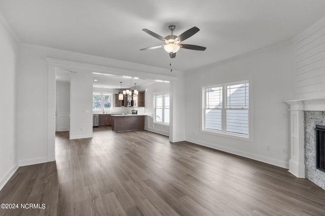 unfurnished living room with ceiling fan with notable chandelier, hardwood / wood-style flooring, a fireplace, and ornamental molding