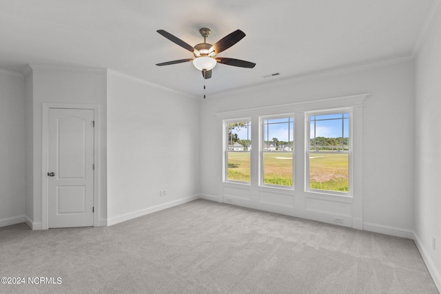 carpeted empty room with ceiling fan, a wealth of natural light, and ornamental molding