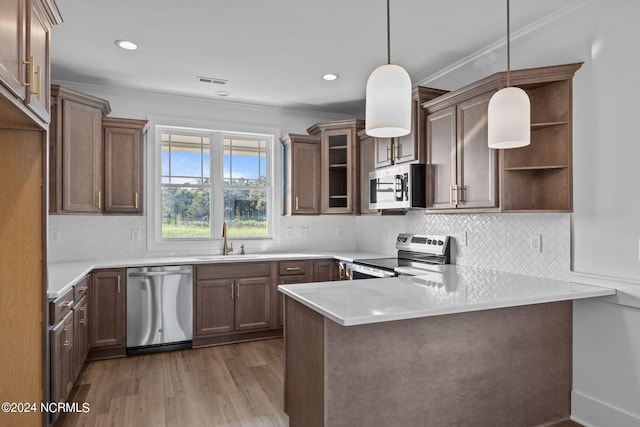 kitchen with stainless steel appliances, sink, wood-type flooring, kitchen peninsula, and decorative backsplash