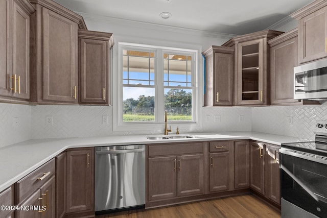 kitchen featuring backsplash, crown molding, appliances with stainless steel finishes, sink, and dark hardwood / wood-style floors