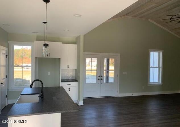 kitchen with white cabinets, dark countertops, dark wood-style flooring, french doors, and a sink