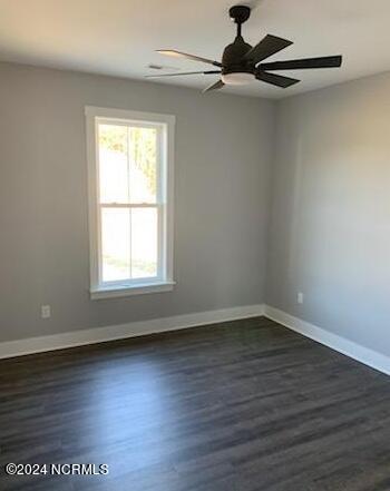 spare room with a ceiling fan, dark wood-style flooring, and baseboards