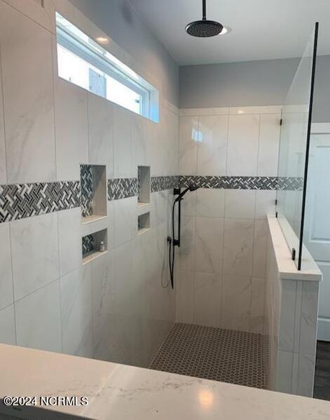 bathroom featuring tiled shower and tile walls