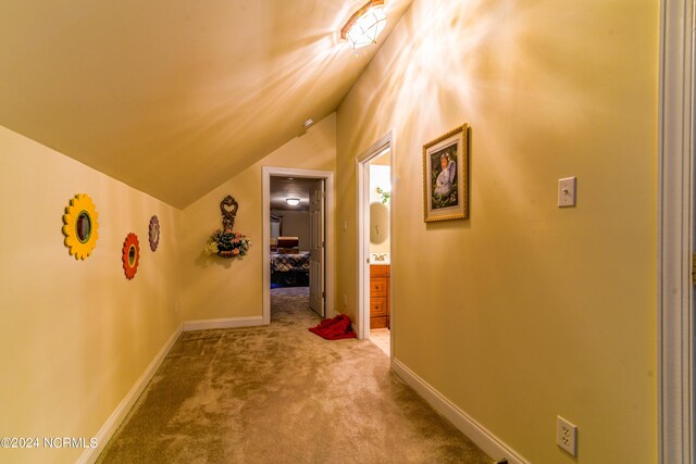 hall featuring carpet floors, baseboards, and lofted ceiling