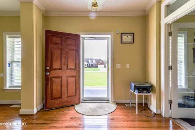 entrance foyer featuring light wood-style floors, baseboards, and crown molding