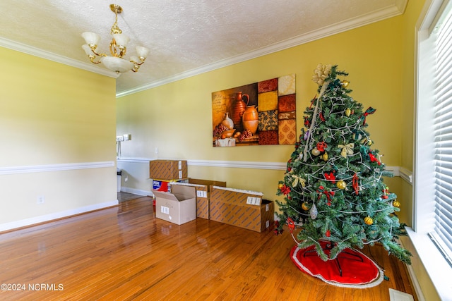 sitting room featuring an inviting chandelier, a textured ceiling, ornamental molding, and wood finished floors