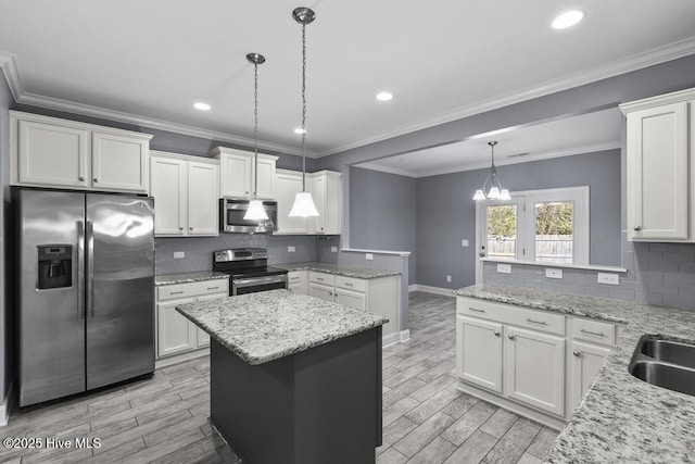 kitchen featuring hanging light fixtures, stainless steel appliances, light stone countertops, white cabinets, and a kitchen island