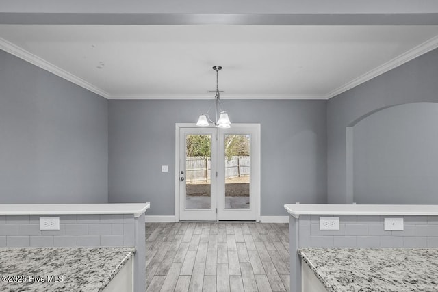 unfurnished dining area featuring crown molding, a chandelier, and light wood-type flooring