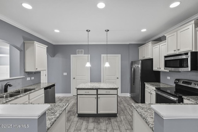 kitchen featuring sink, a center island, appliances with stainless steel finishes, pendant lighting, and white cabinets